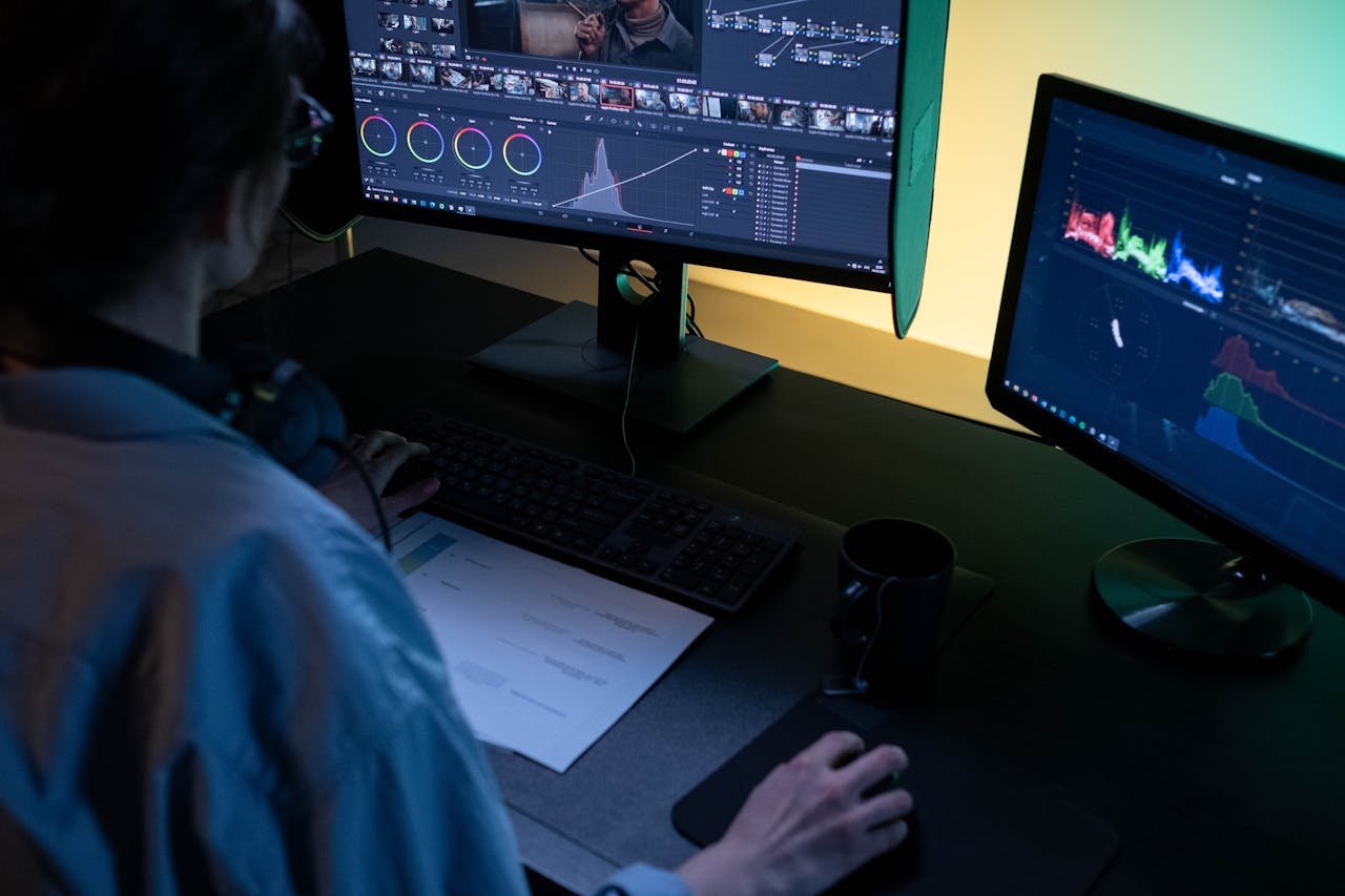 about-us-01 A video editor using dual monitors for editing footage in a dimly lit studio.
